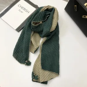 Detail of green and khaki pleated scarf featuring delicate mini tassel ball charms