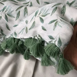 Detail of green leaf print on breathable linen-blend scarf with fringe trim