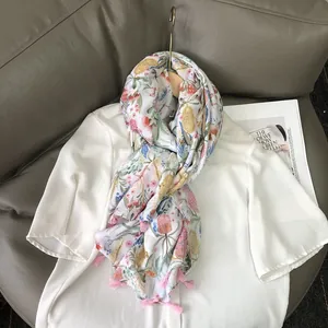 Lightweight floral print scarf with pink tassels draped over a white shirt on a hanger