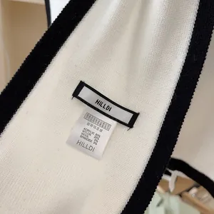 Detail view of garment care label and material composition on white knit shrug