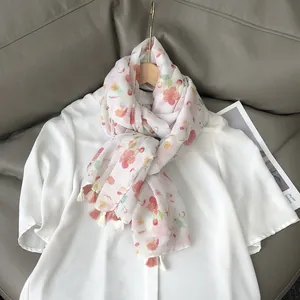 Floral cotton linen scarf with cherry blossom patterns and tassels on white shirt