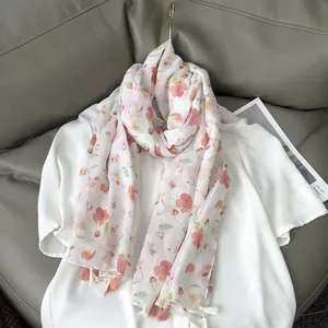 Floral cotton linen feel scarf with tassels displayed on a grey leather sofa
