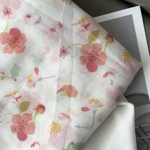 Detailed texture of lightweight white scarf with pink cherry blossoms and floral pattern