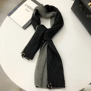 Detail of two-tone linen scarf featuring pleated texture and pom-pom fringe charms