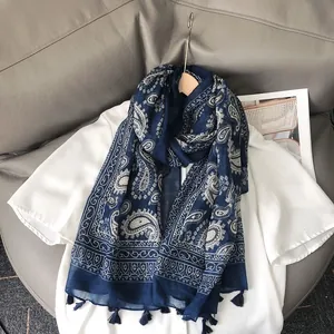 Dark blue paisley Bali yarn scarf with fringe tassels over a white shirt backdrop