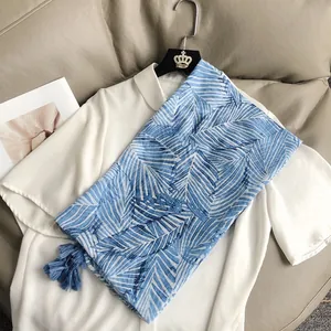 Châle à imprimé feuilles de palmier bleues avec glands sur chemise et canapé