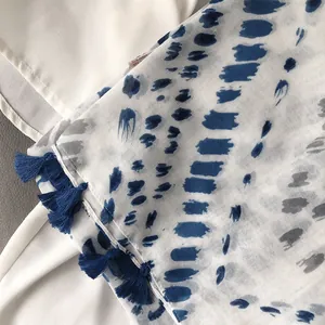 Détail d'écharpe en coton et viscose à pois bleus avec des franges à pompons doux