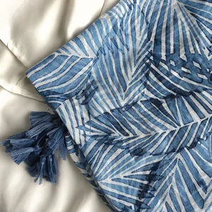 Détails d'un châle bohème à imprimé feuilles de palmier bleues avec des glands