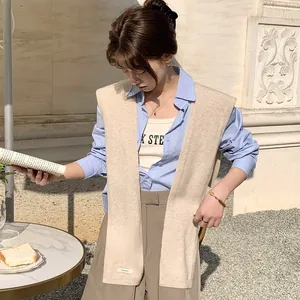 Scialle beige in 100% lana australiana lavorata a maglia sopra una camicia azzurra in stile street