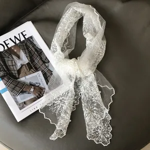 Elegant white floral lace scarf with embroidery and scalloped edges on leather background