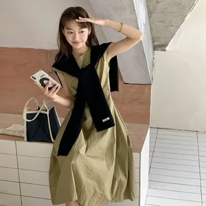 Elegante abito smanicato verde oliva abbinato a uno scialle di lana nero a maglia da donna