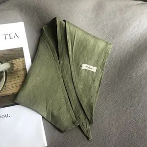 100% pure linen scarf in dark green on gray leather background with a magazine