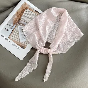 Dettaglio di bandana in pizzo rosa con ricami floreali farfalle e bordi ondulati