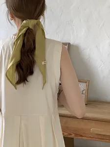 Detail of 100% pure linen mustard scarf tied on a ponytail with a white woven label