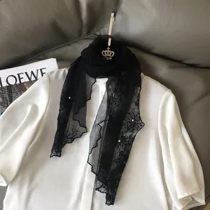 Detail of black floral lace scarf with pearl accents on a white short-sleeve shirt
