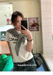 Detalle de camiseta blanca con estampado y un chal triangular de lana gris premium