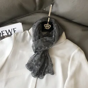 Detail eines grauen Schals mit Blumenspitze und Wellenrand auf weißem Hemd präsentiert