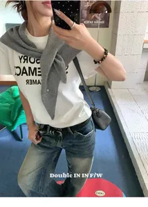 Detalle de chal triangular de lana gris combinado con camiseta blanca y vaqueros