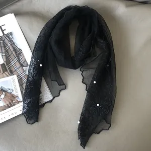 Detail of black lace scarf with pearl accents on a minimalist leather background