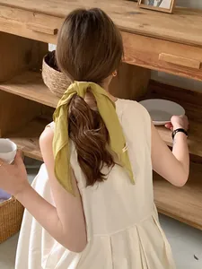 Close-up of yellow linen scarf tied as a hair accessory on ponytail in lifestyle setting