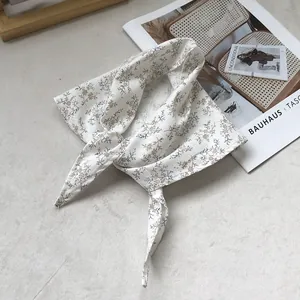Linen floral triangle neck scarf displayed on a minimalist background with art books