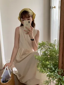 Close-up of a minimalist cream linen sleeveless maxi dress with a woven straw basket