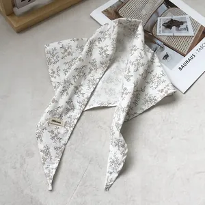 Detailed close-up of a 100% linen triangular floral scarf with refined stitching