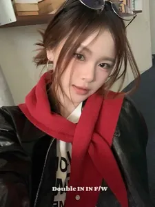 Detalle de un chal de lana rojo oscuro combinado con una chaqueta de cuero negro