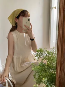 Close-up of minimalist cream sleeveless linen dress styled with a ginger cotton headscarf