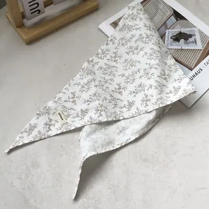 Detail view of 100% linen triangle scarf with delicate blue and brown floral patterns