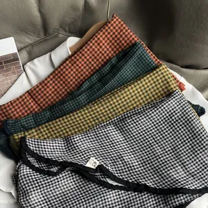 Detailed view of plaid cotton scarves with stitched edges in multiple colors on a sofa