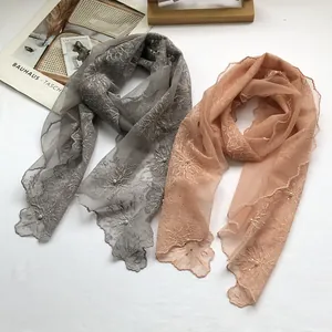 Detail of grey and pink lace scarves with floral embroidery and white pearl accents