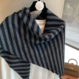 Bufanda triangular minimalista de lana a rayas en percha con elegante bolso de cuero