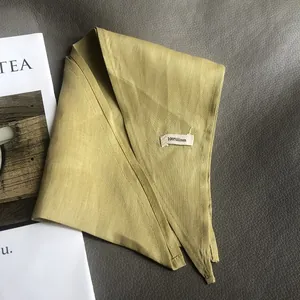 Olive green 100% pure linen triangular scarf flat lay on a minimalist dark background