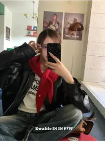 Detalle de un pañuelo triangular de lana roja como chal sobre una chaqueta de cuero
