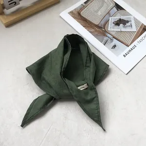 Detail of green linen triangle scarf featuring a delicate leaf print and quality stitching
