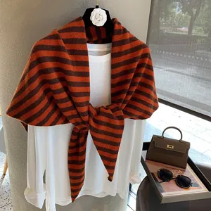 Detalle de chal de lana a rayas naranjas y marrones sobre una camiseta blanca clásica