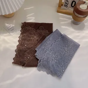 Detailed embroidery on lace scarf with delicate floral patterns and pearl accents