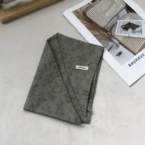 Close-up of 100% linen triangle scarf with olive green floral pattern and fabric texture