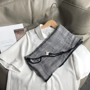 Detail of a black and white gingham cotton scarf paired with a white Peter Pan collar shirt