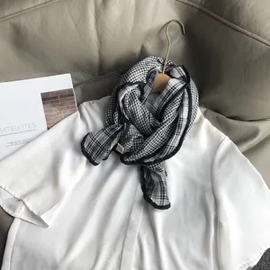 Detail of a black and white checkered cotton scarf styled on a white shirt collar