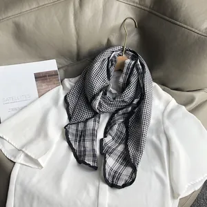 Detail view of a black and white checkered cotton neck scarf on a white shirt