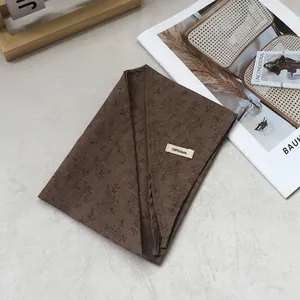 Close-up of a 100% linen brown floral neck scarf with branch prints and a fabric label