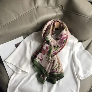 Châle léger en coton et lin avec imprimé floral rose et bordure verte sur cintre en bois