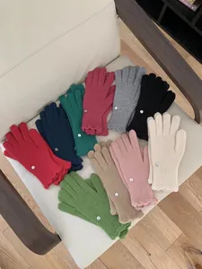 Detail of colorful knitted touchscreen gloves featuring decorative buttons and wavy cuff edges