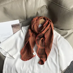 Detail of checkered cotton scarf with vintage pattern and a round brand tag on white shirt
