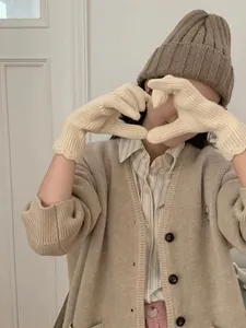 Detail view of off-white knitted touchscreen gloves with wave cuffs and winter outfit