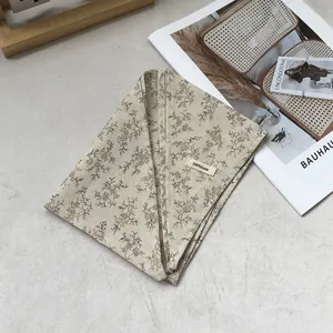 Detailed view of folded 100% linen triangle scarf with floral print and fabric label