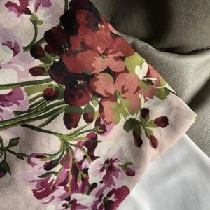 Détail d'une écharpe fleurie en coton et lin avec fleurs roses et bords roulés