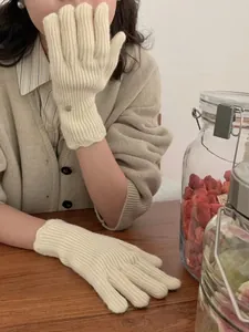 Close-up of cream knit gloves with vertical ribs and elegant wavy scalloped wrist cuffs